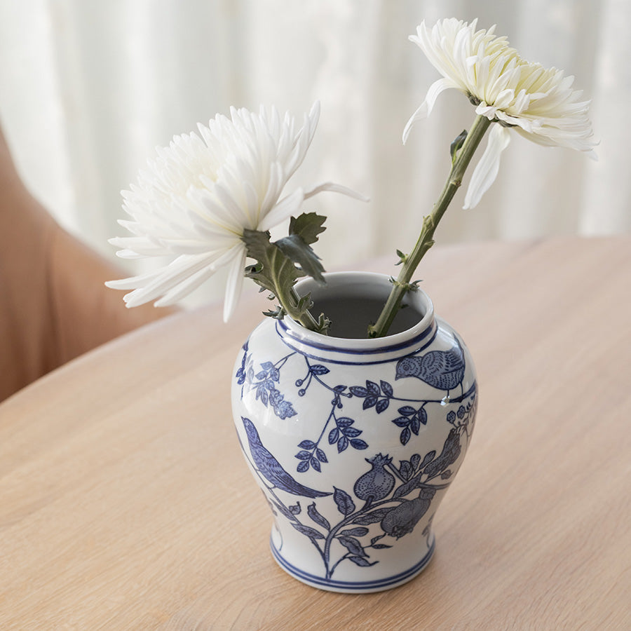 Mingkrukke i blått med blomster i, står på et bord og viser det håndmalte mønsteret som gir en elegant interiørdetalj.