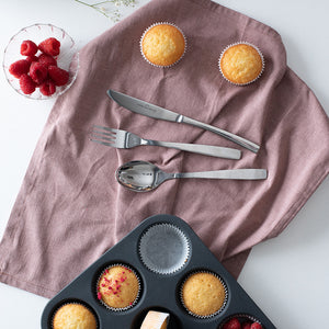 Christiania Bestikk Torino bestikk med kniv, gaffel og skje på linserviett sammen med nybakte muffins