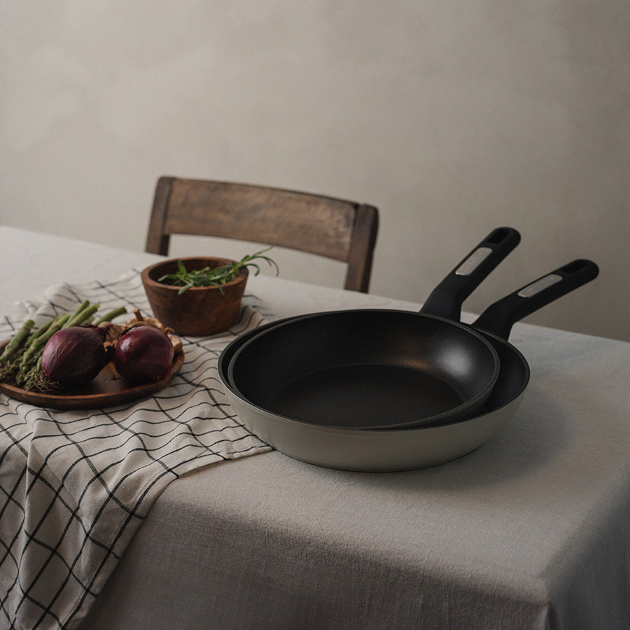 Christiania 1739 Plus Stekepanne 28cm Beige - To stekepanner plassert på et bord, fremhever det stilrene designet og allsidigheten til stekepannen.