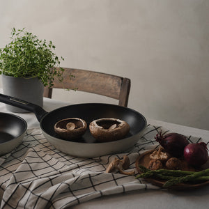 Christiania 1739 Plus Stekepanne 28cm Beige - Stekepannen i bruk med grønnsaker, på en dekket bord med naturlig lys, ideell for matlaging.