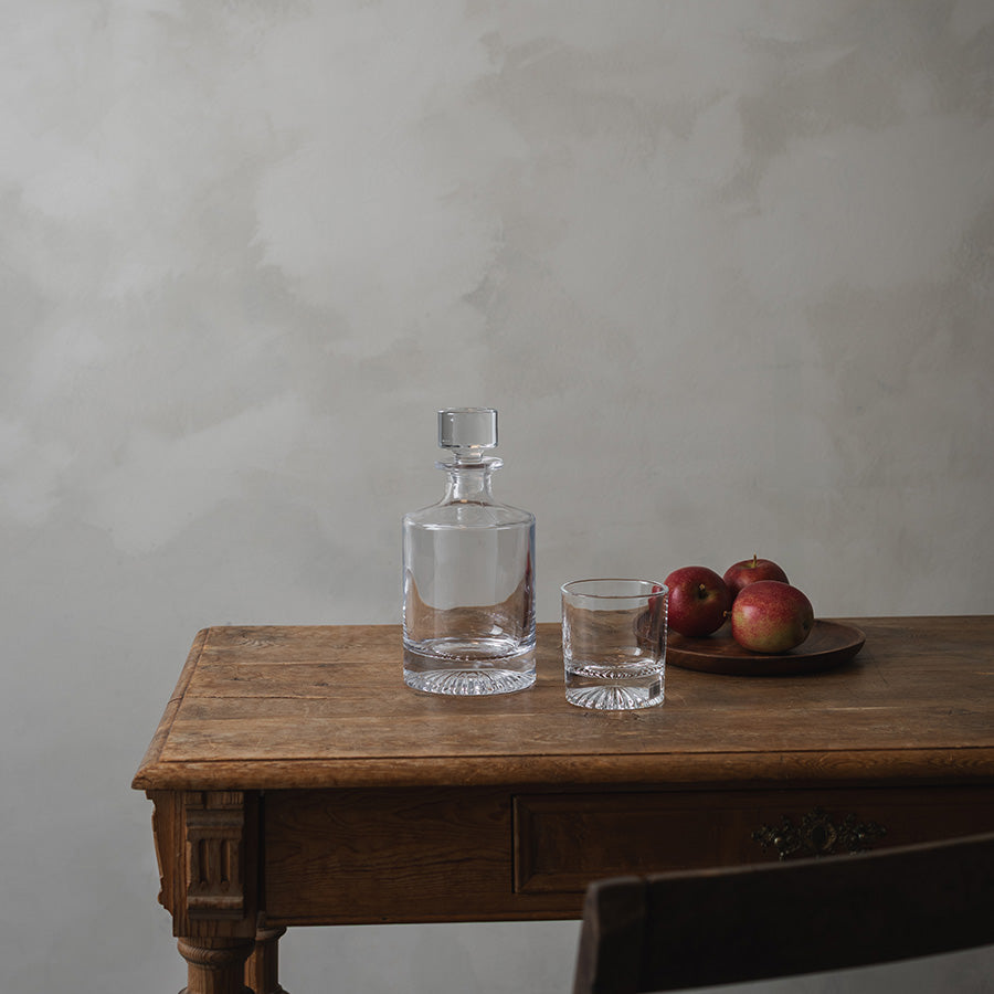 Christiania 1739 whiskeyglass på en treplate, sammen med en karafle og epler, som viser et tidløst og stilrent design.