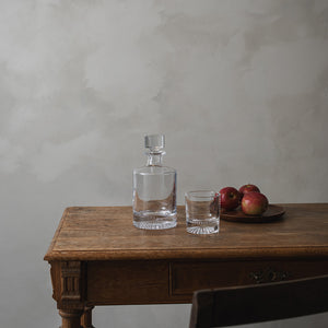 Christiania 1739 whiskeyglass på en treplate, sammen med en karafle og epler, som viser et tidløst og stilrent design.