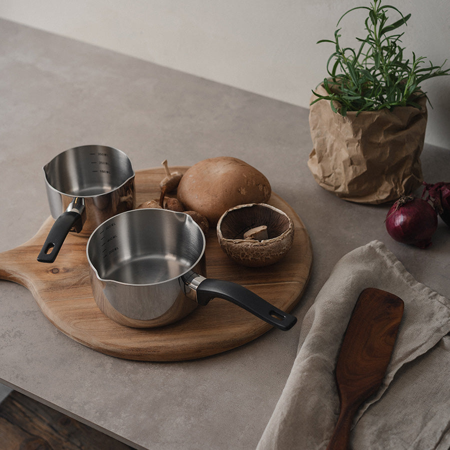 Christiania 1739 Chef's Choice Kasserolle m/Helletut 700ml plassert på en kjøkkenbenk med grønnsaker og et skjærebrett.