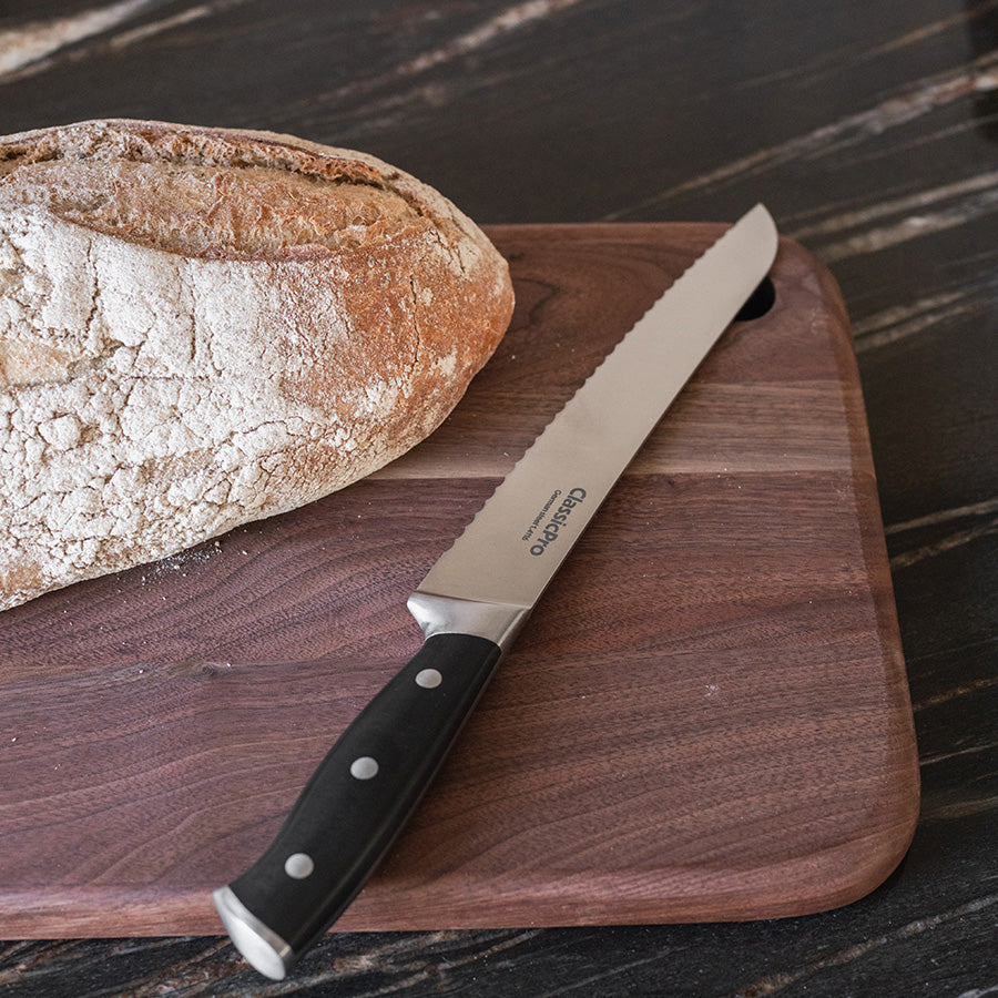 ClassicPro brødkniv i bruk, skjærer gjennom ferskt brød på en tre skjærebrett.