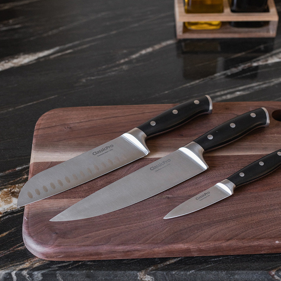 Tre ClassicPro kokkekniver med ergonomiske håndtak på skjærebrett, perfekt for matlaging.