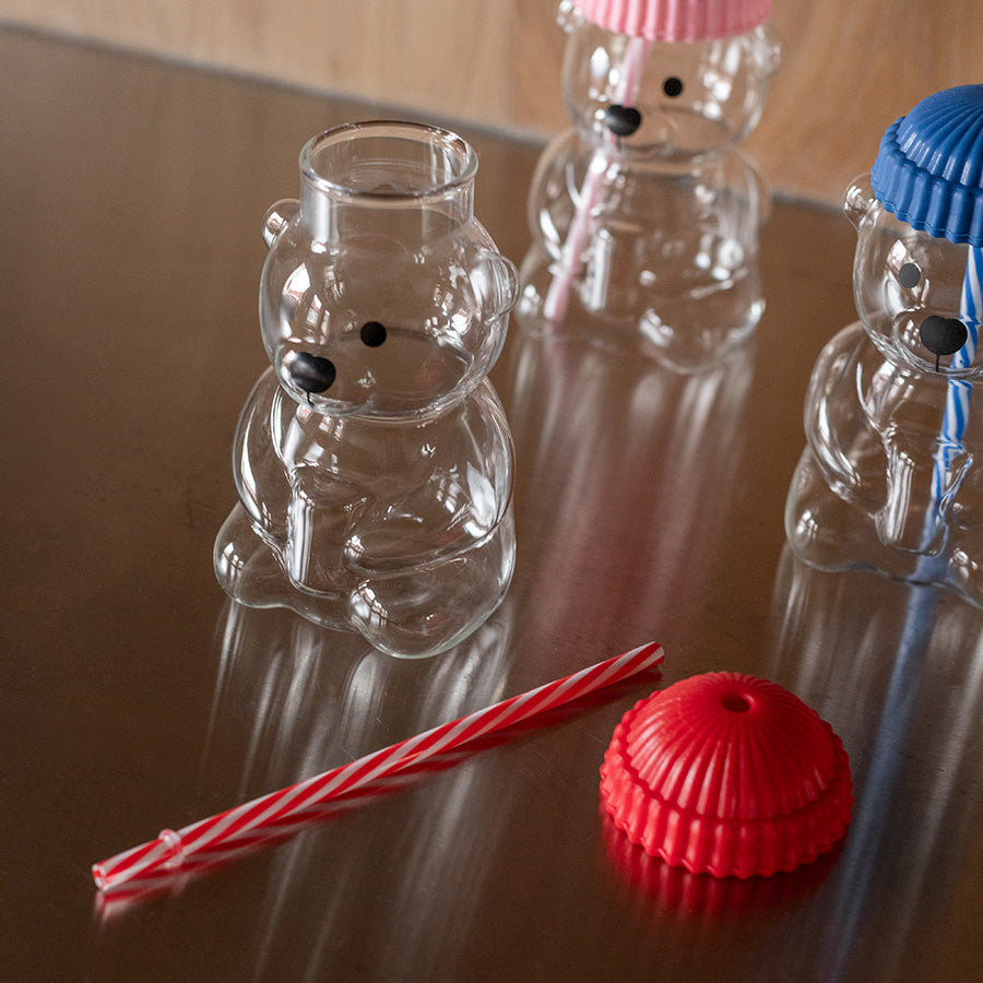 Åpent bjørneformet glass med rød silikonhatt og sugerør sammen med to andre fargede glass, ideal for barnebursdager.