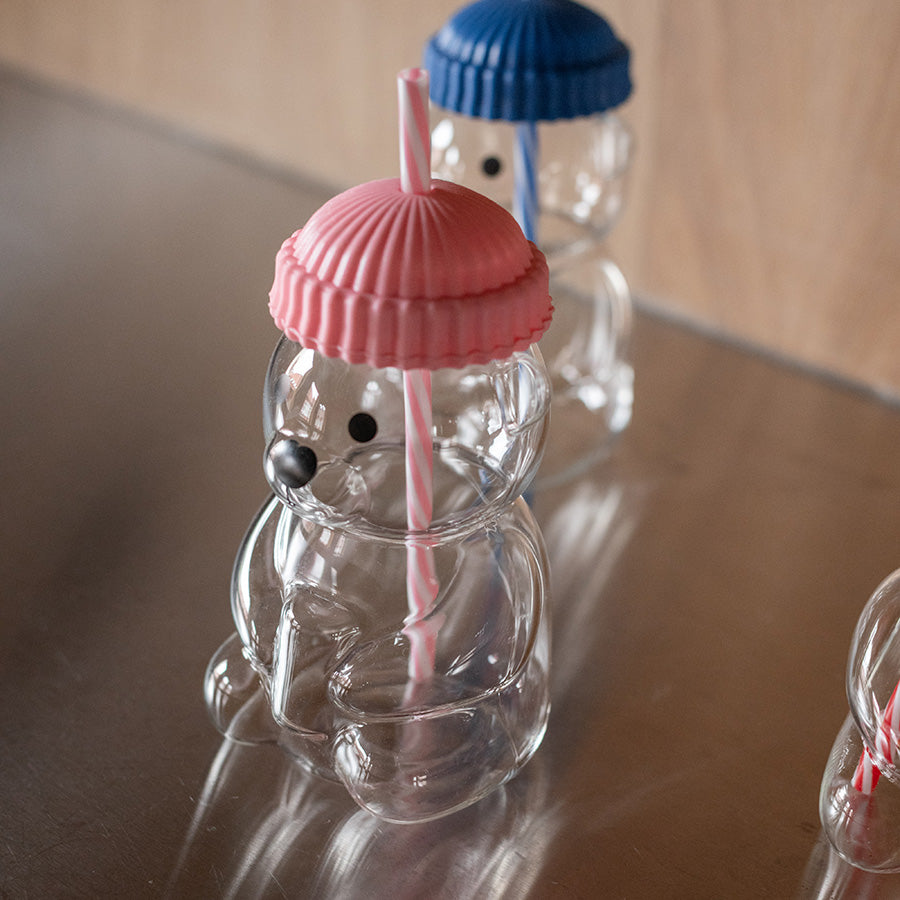 Detaljert bilde av bjørneformet glass med rosa silikonhatt og sugerør, perfekt for søte drikker.