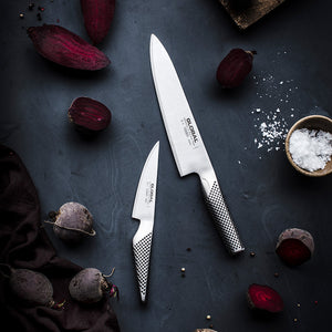 Global knivsett bestående av kokkekniv G-2 og universalkniv GS-1, plassert på en mørk overflate med rødbeter, perfekt for hjemmekokker.