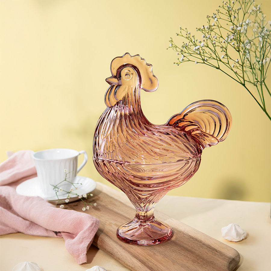 Elegant rosa glasshane i klassisk design, plassert på en treplate med en kopp i bakgrunnen, ideell til påskepynt og dekorgegenstander.