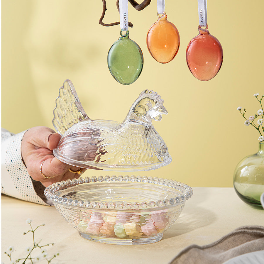 Åpen Hadeland Glassverk verpehøne skål med lokk, dekorert og fylt med påskegodt, inspirerende påskedekor.