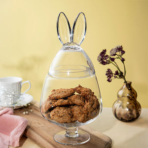 Glassegg fylt med småkaker, dekorativt plassert på et bord med blomster i bakgrunnen.