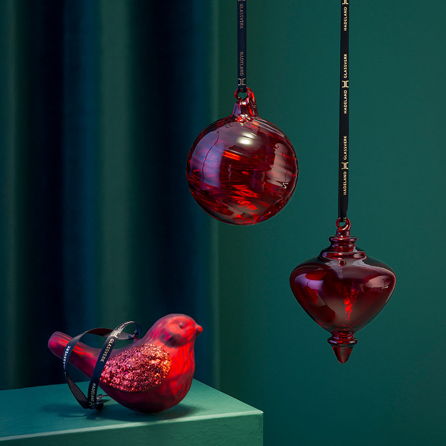Elegant Hadeland Glassverk Fugleklang julepynt, med en glitrende fugl og to glasskuler i rødt, som skaper en klassisk julestemning.