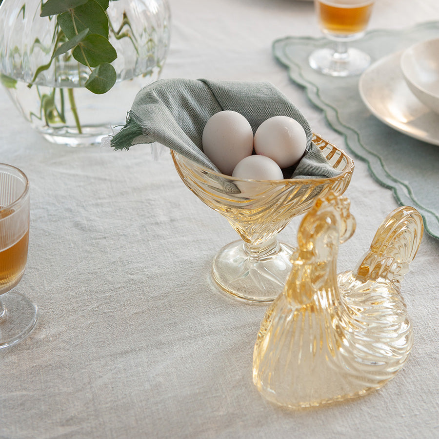 Glasshane med små hvite egg, i en koselig setting med grønne detaljer.