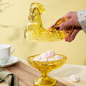 Hendel av glasshane i gullfarget glass, fylt med småkaker, i et stilfullt miljø.