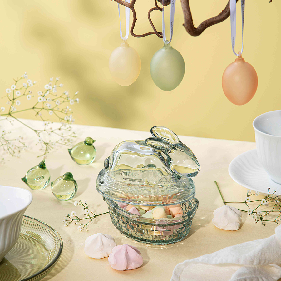 Dekorativ Kaninskål med hare-lokk fra Hadeland Glassverk, fylt med påskegodt, plassert på et festlig bord med påskeegg og blomster.