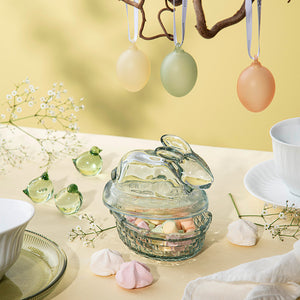 Påskekyllinger i glass plassert på et bord sammen med dekorative påskeelementer.