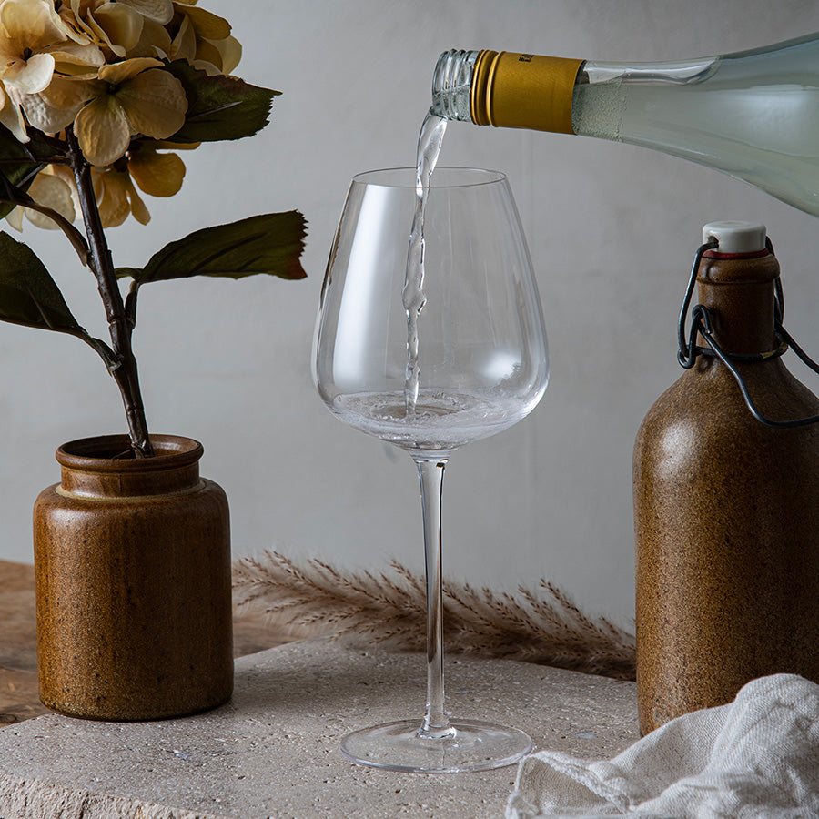 Hadeland Glassverk Odyssé Allroundglass 56cl 6pk fylles med vin fra en flaske, fremhever det allsidige designet for vinelskere.