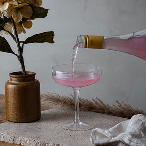 Hadeland Glassverk Odyssé Cavaskål 25cl 6pk fylt med rosa drikke fra en flaske. Skålen er perfekt for servering av musserende drikke og gir en elegant fremtoning.
