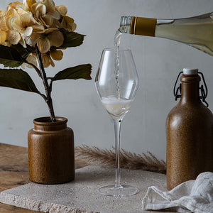 Hadeland Glassverk Odyssé champagneglass 32 cl under servering av champagne fra en vinflaske, illustrerer det stilige designet og funksjonaliteten til glassene.