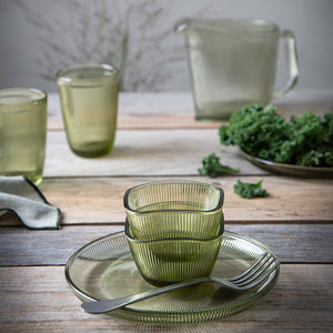 Hadeland Glassverk Siri Bolle 9,5cm, grønn, plassert på bordet med andre glassprodukter, viser kombinasjon av stil og funksjonalitet.