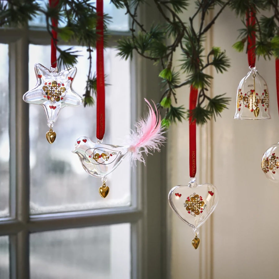 Holmegaard julefugl med rosa fjær blant håndlagde glassornamenter på juletre