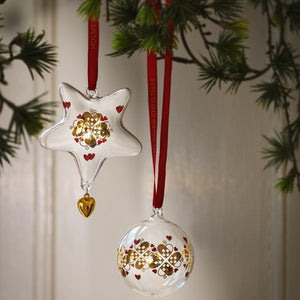 Holmegaard julestjerne i glass med gylne detaljer og hjerteanheng, dekorert på juletre sammen med matchende julepynt