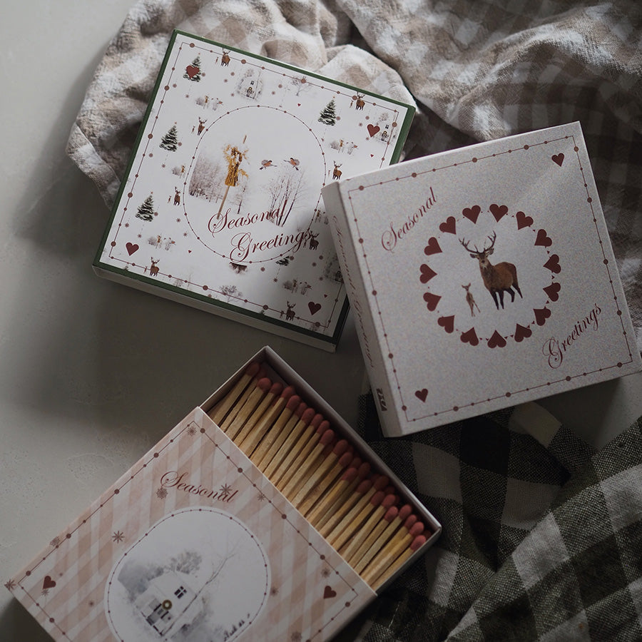 Åpen eske med lange fyrstikker fra Wik & Walsøe Julemorgen-serien, vist sammen med dekorative juleesker