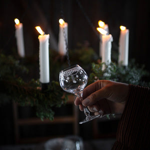 Julemorgen akevittglass fra Wik & Walsøe holdes i hånden foran tente julelys