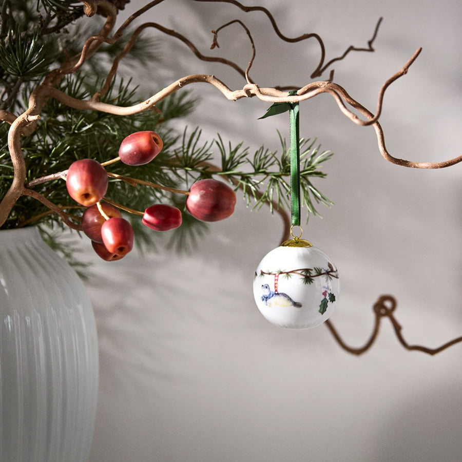 Kähler Hammershøi Jul 2026 julekule hengende på en gren med røde bær og vinterlig juledekor