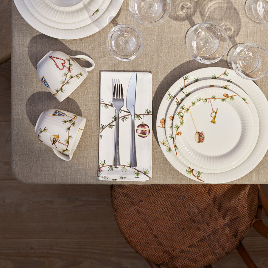 Elegant borddekk med Kähler Hammershøi Christmas stoffservietter, keramiske tallerkener og glass, alt i en koselig juleinnstilling.