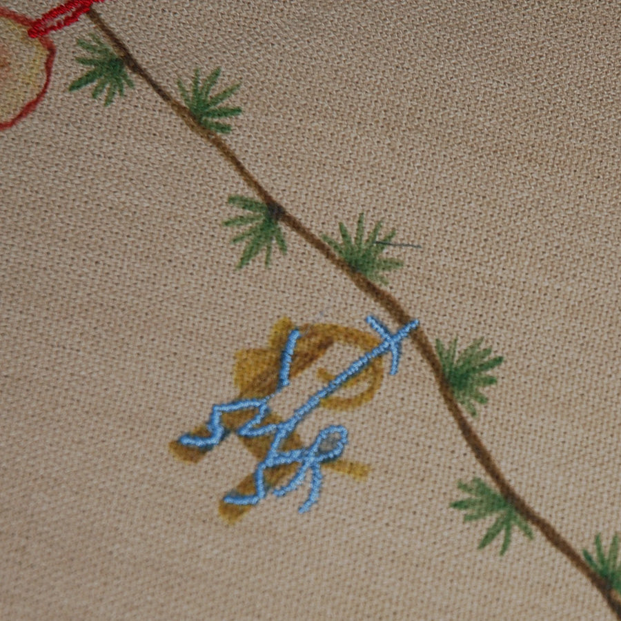 Detaljbilde av broderte julemotiver og granbar på sandfarget Kähler juletreteppe