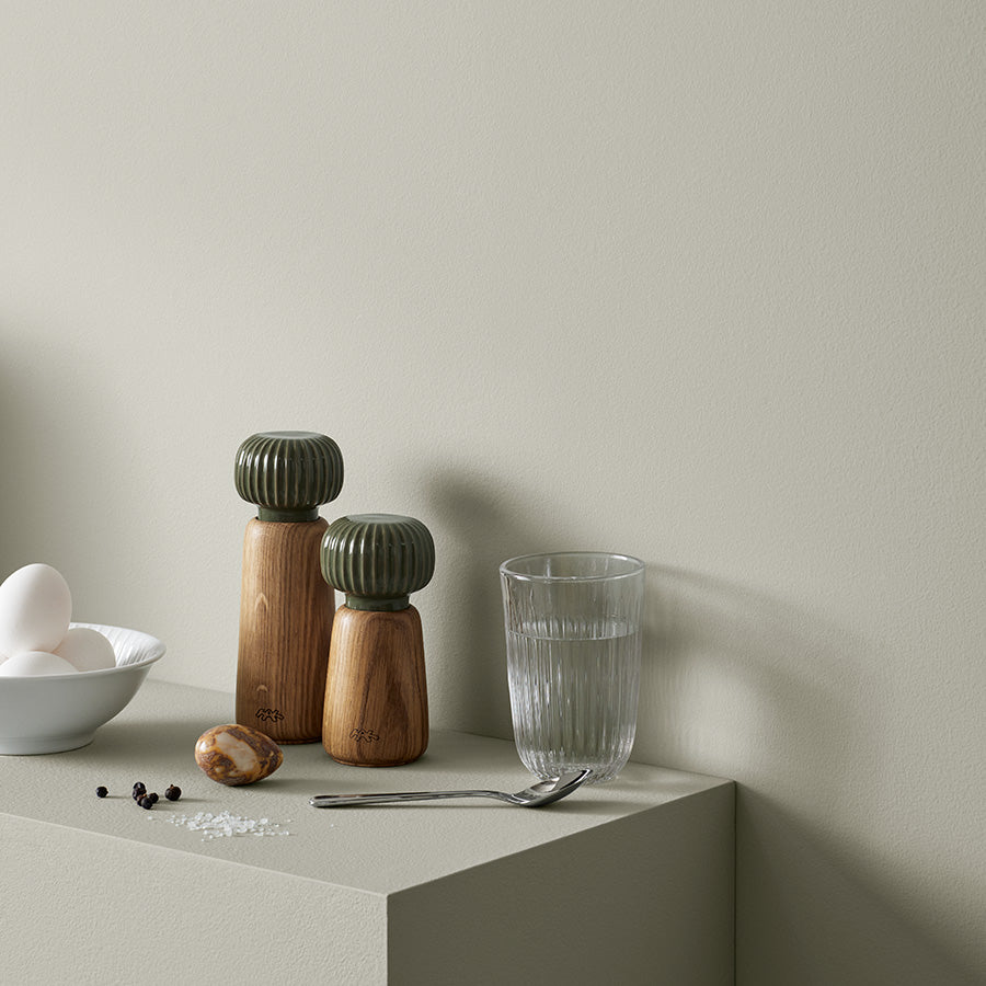 Kähler Hammershøi skål 16cm i hvit plassert på en moderne kjøkkenbenk, med tilbehør som krydderkverner og glass.