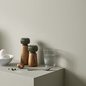 Kähler Hammershøi skål 16cm i hvit plassert på en moderne kjøkkenbenk, med tilbehør som krydderkverner og glass.