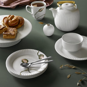 Kähler Hammershøi kakefat på stett 30 cm i hvit porcelen som vises i en koselig setting med kaker og te, perfekt for servering av søte fristelser.