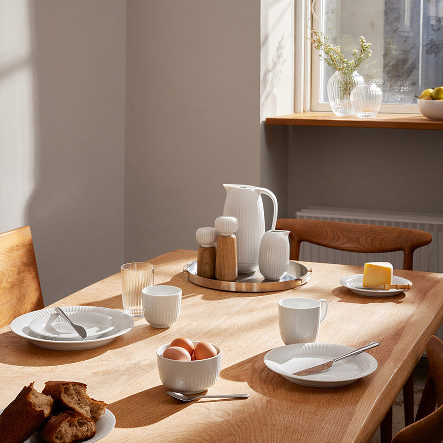 Kähler Hammershøi Mugge 50cl Hvit plassert på et dekket bord med ulike servise, ideell for frokost eller middag.