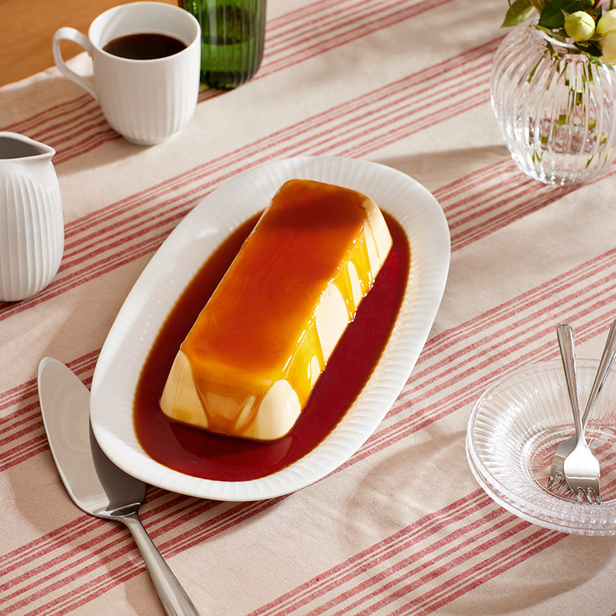 Kähler Hammershøi ovalt serveringsfat 40x22,5 cm i hvit, dekorert med karamellpudding, ideelt fat for servering.