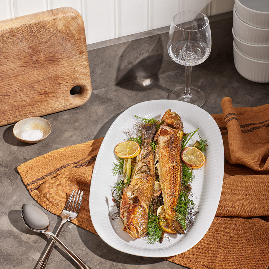 Kähler Hammershøi ovalt serveringsfat 40x22,5 cm i hvit, med grillet fisk og grønnsaker, perfekt til festlig servering.