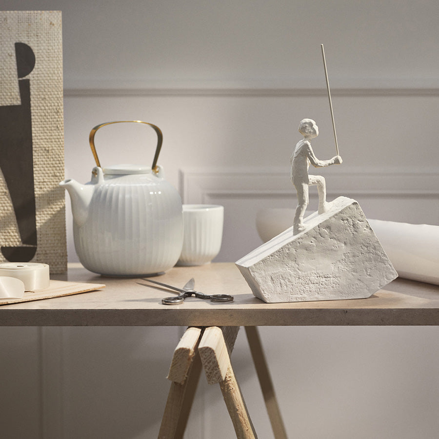 Kähler Hammershøi tekanne som står på et bord i et stilrent interiør, med rillede detaljer som fremhever den nordiske elegansen.