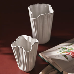 Kähler Hammershøi Unfold vase 16,5 cm hvit sammen med en mindre vase, illustrerer den elegante designen på et bord.