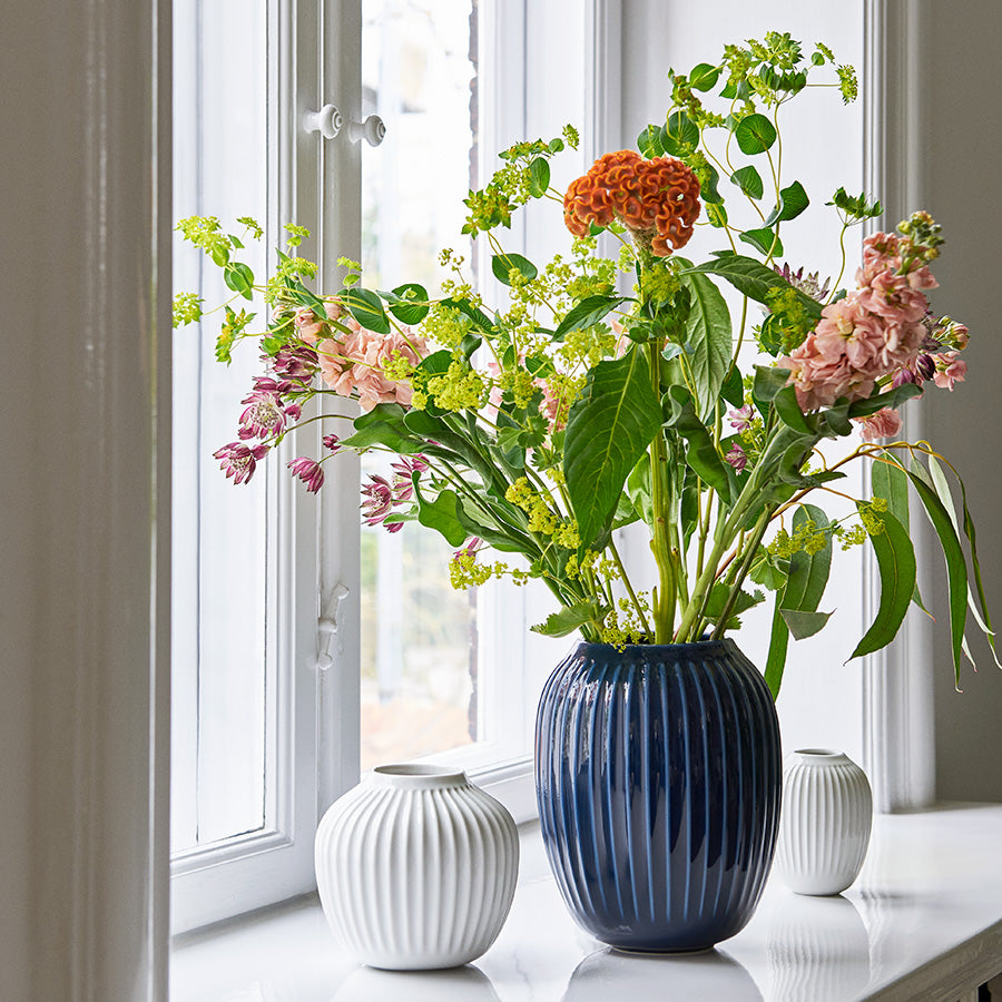 Kähler Hammershøi vase 10,5cm Hvit med blomster i vinduskarmen, skaper en vakker atmosfære.