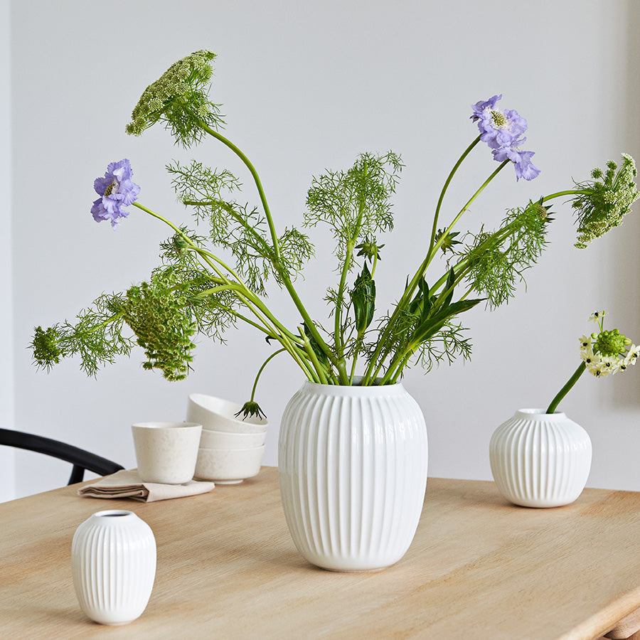 Kähler Hammershøi Vase 25,5 cm i hvit, med blomsterarrangement, plassert på spisestuebordet, uttrykker moderne skandinavisk design.