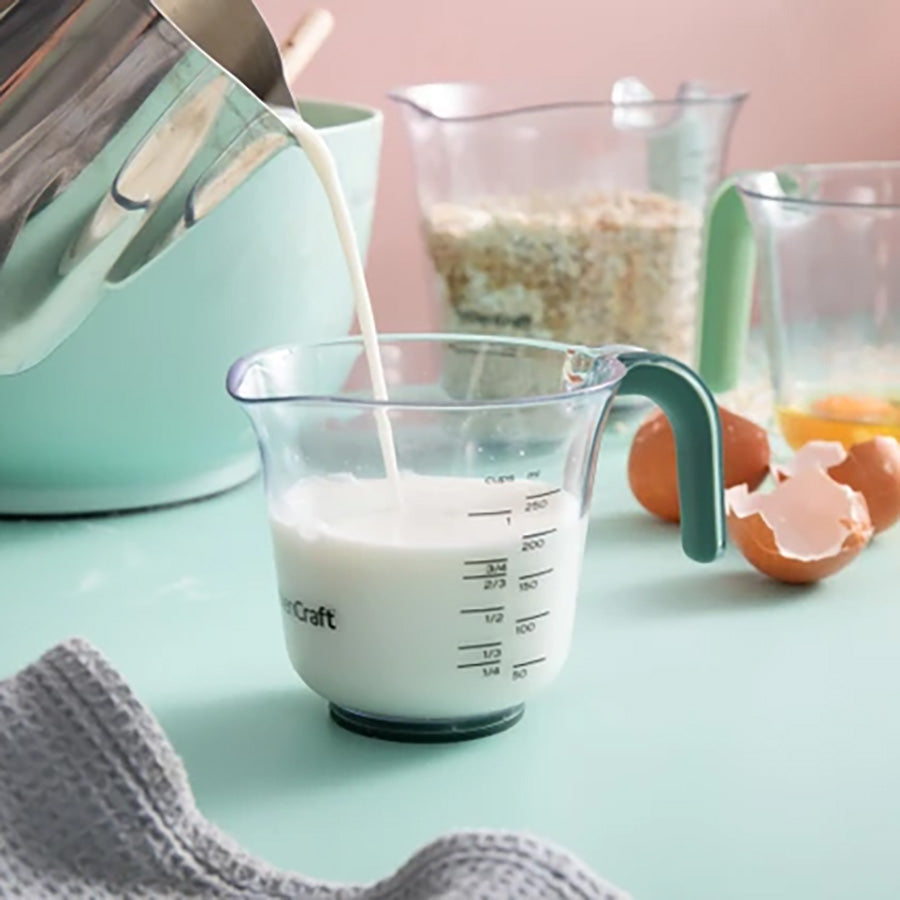 Målebeger med tydelige målemarkeringer fylles med melk til baking