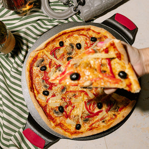 Delikat pizza på Lodge Cast Iron pizzastein, noen skjærer ut en bit.