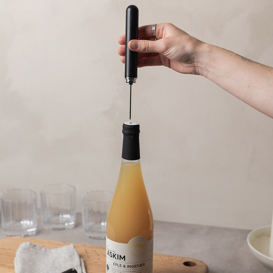 Sort vinåpner med luftpumpe i bruk på en vinflaske
