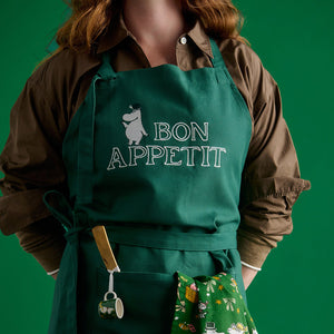 Grønt Mummi forkle med Mummipappa og Bon Appétit-trykk i bruk på kjøkkenet