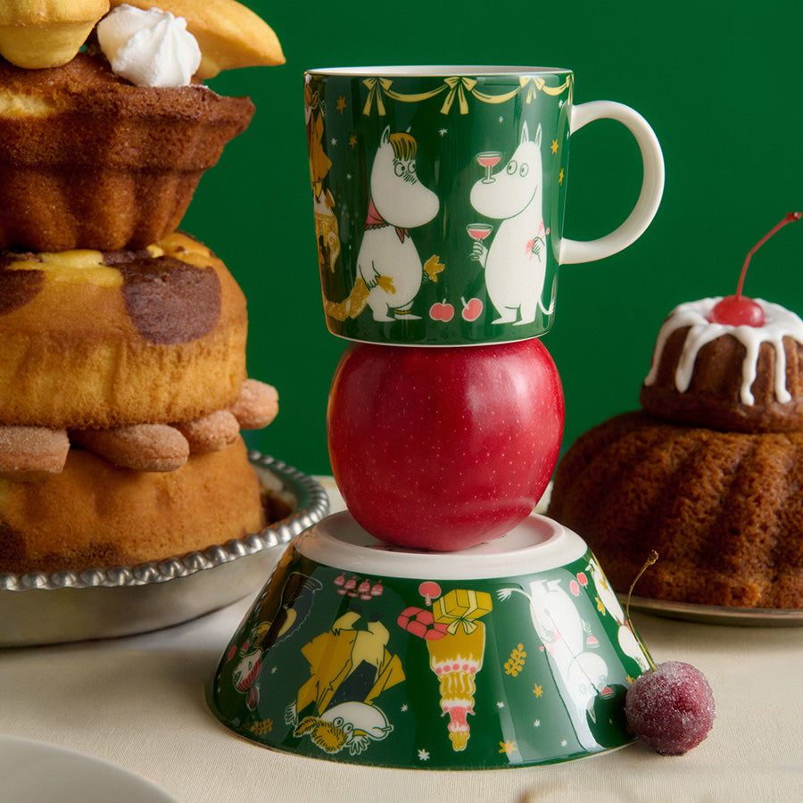 Mummi kopp fra Moomin Arabia med grønt festdesign, omgitt av kaker og desserter