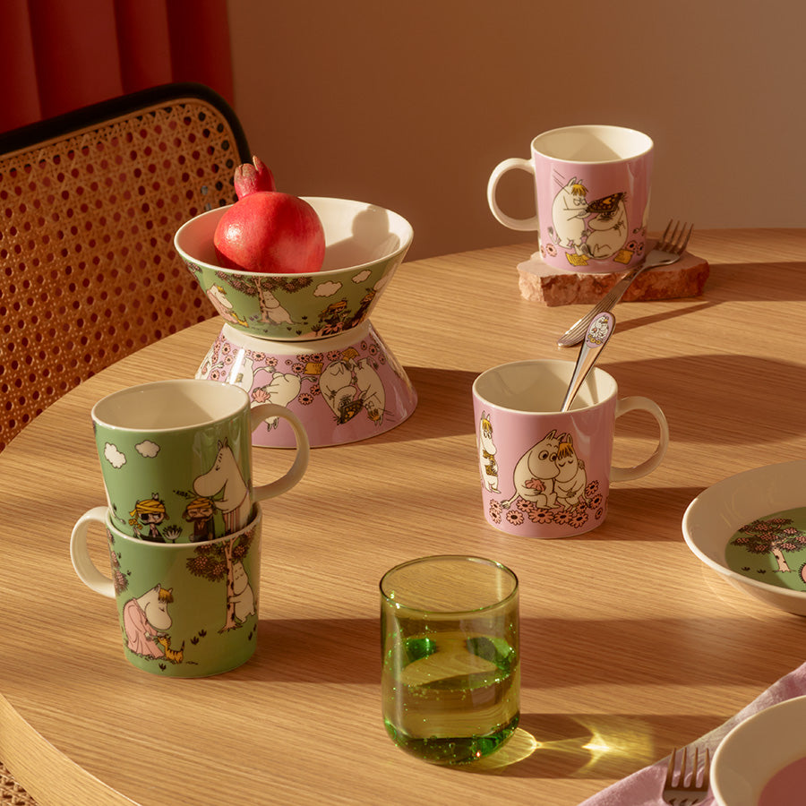 Mummi bolle plassert på et bord med Mummi-kopper og en granateple, ideelt for frokost og koselige samlinger.