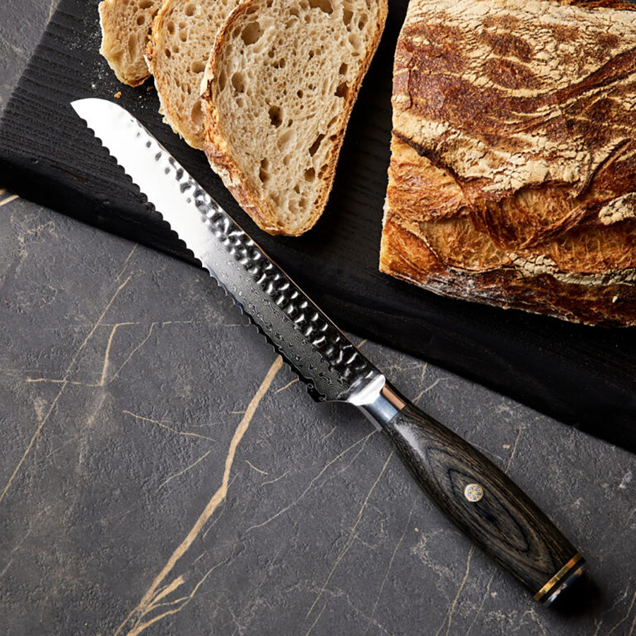 Nordic Blades brødkniv sammen med rustikt brød, viser knivens presisjon og skarpe taggete egg for effektiv kutting.