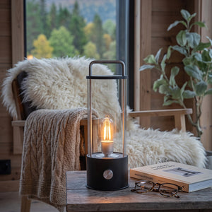 Ledlampe 31 cm i sort med varmt lys på sidebord i lun stue