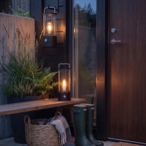 Ledlampe i sort ved inngangsdør og terrasse med stemningsfull belysning